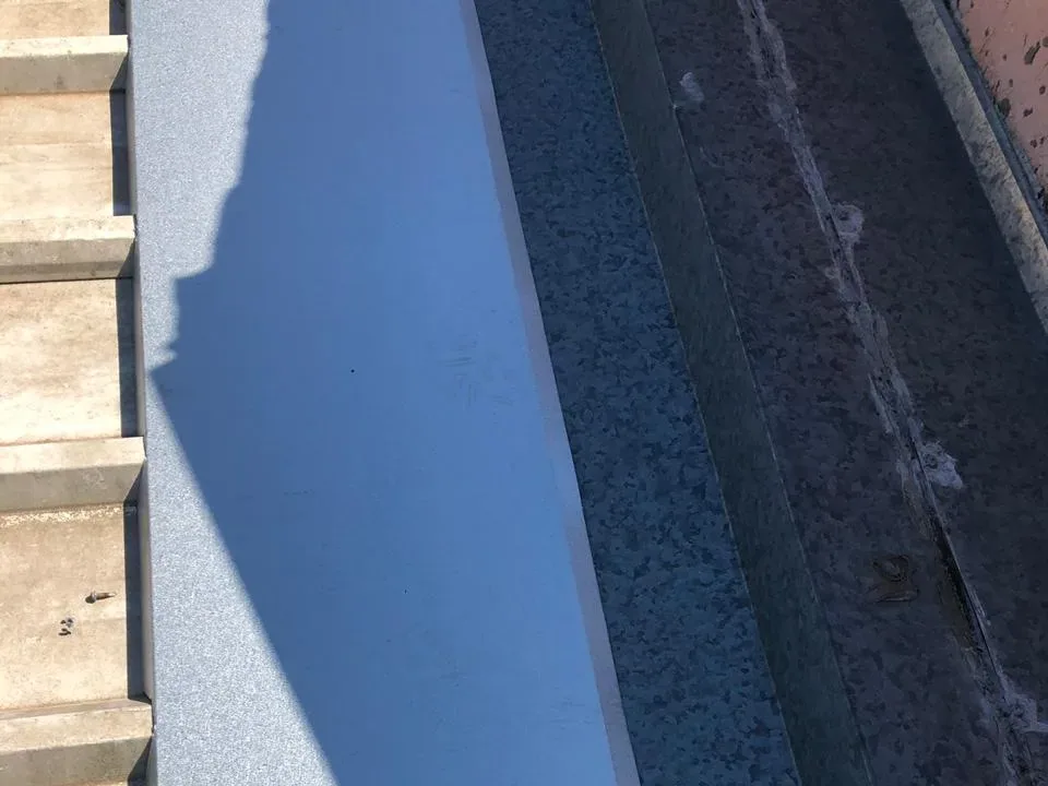 Calha metálica em detalhe durante serviço de troca no telhado